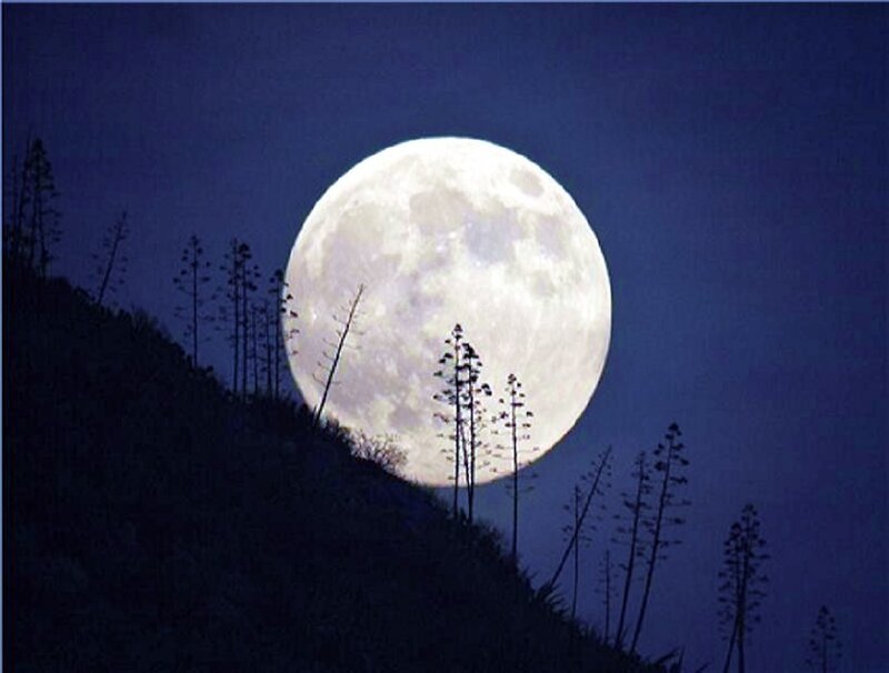 Full moon over silhouetted hill