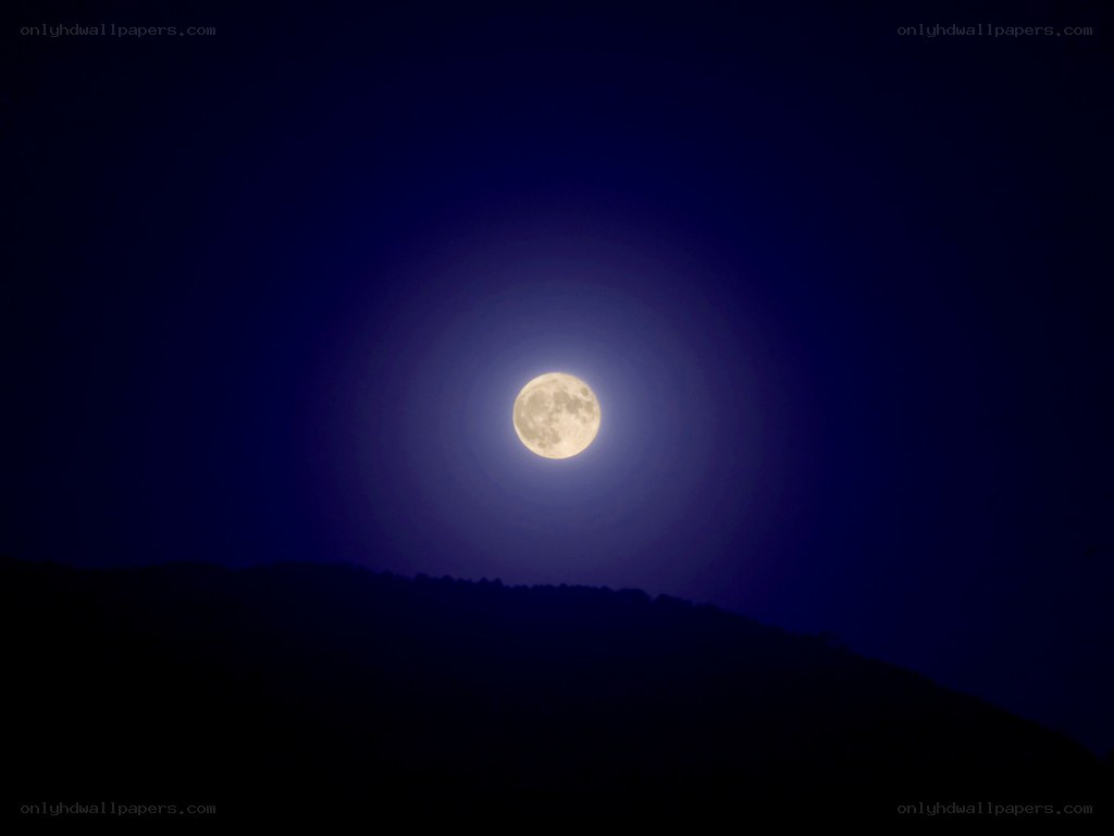 Full moon over silhouetted hills