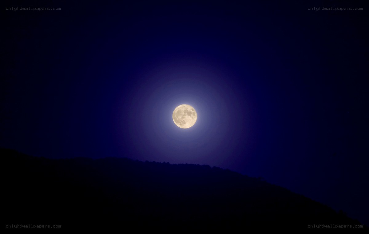 Full moon over silhouetted hills