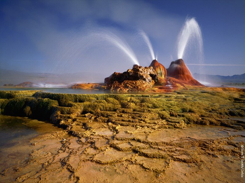 geyser erupting in colorful landscape