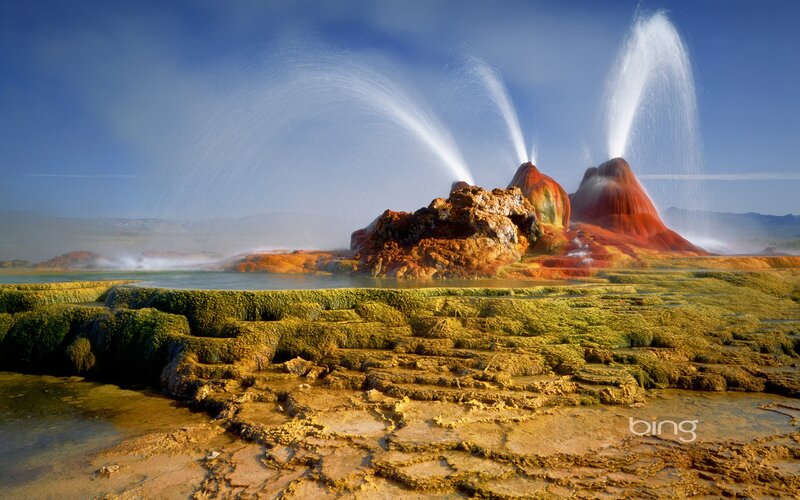 Geysers erupting in colorful landscape