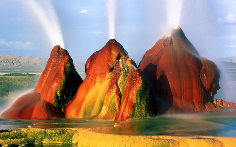 Geysers erupting in colorful landscape