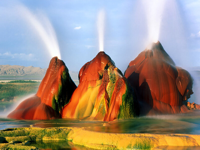 Geysers erupting in colorful landscape
