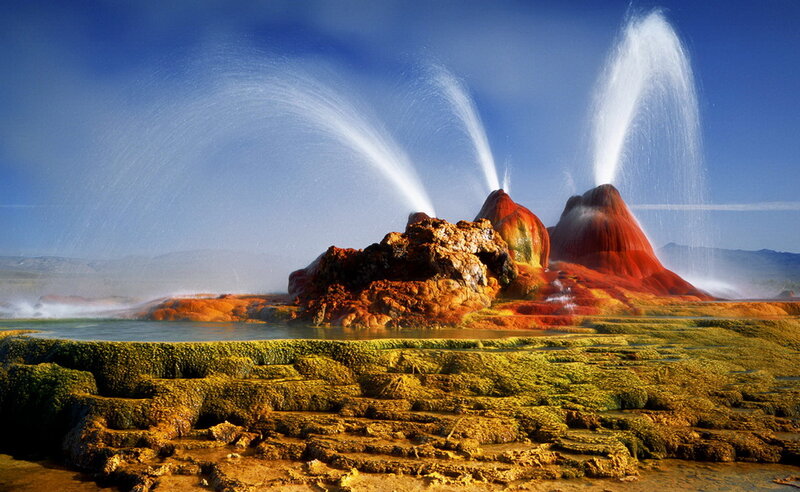 Geysers erupting in colorful landscape