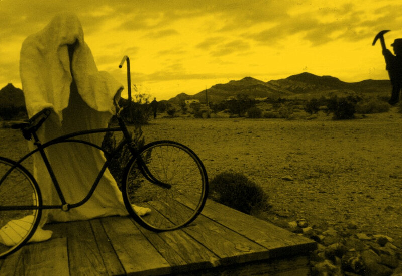 Ghostly figure with bicycle in desert