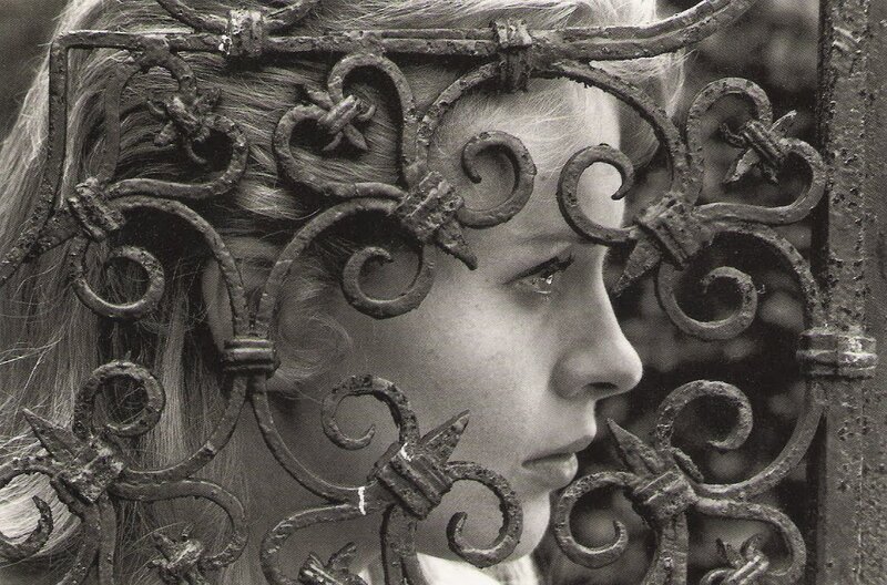girl behind wrought iron gate