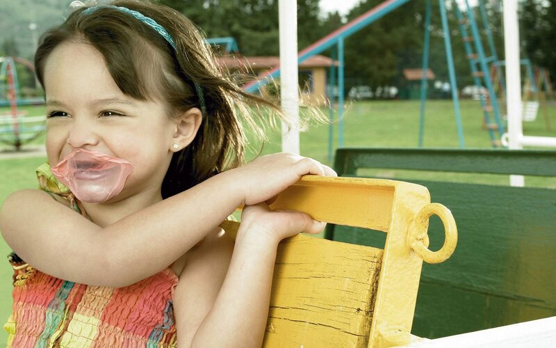 girl blowing bubble gum at playground