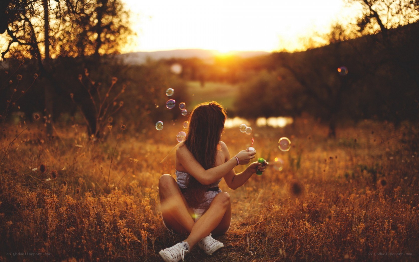 Girl blowing bubbles at sunset