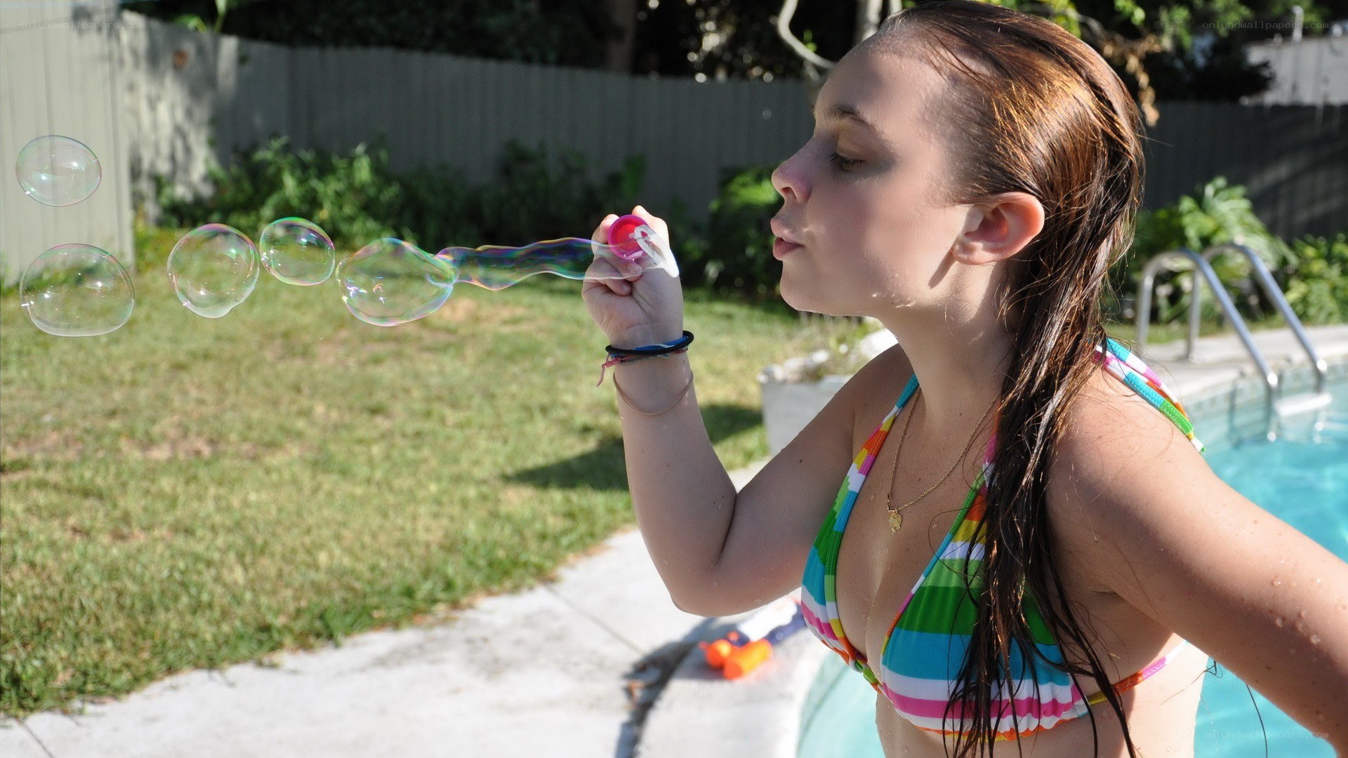 Girl blowing bubbles by pool