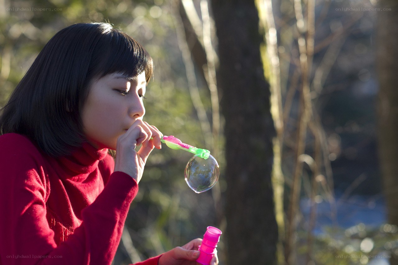 Girl blowing bubbles in forest