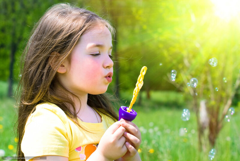 girl blowing bubbles in park