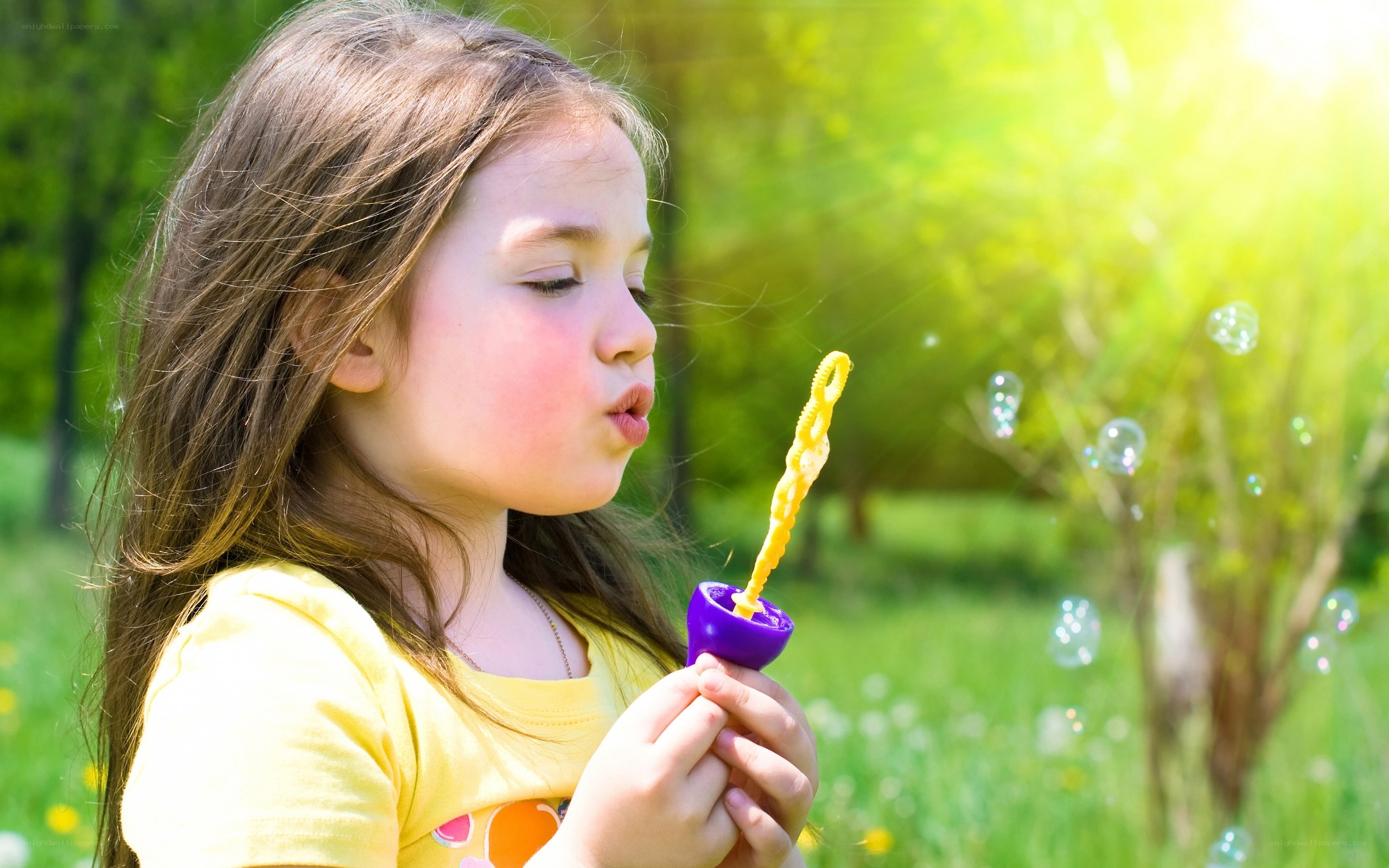 girl blowing bubbles in park
