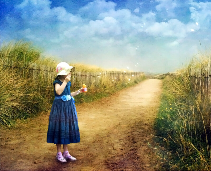 Girl blowing bubbles on a path