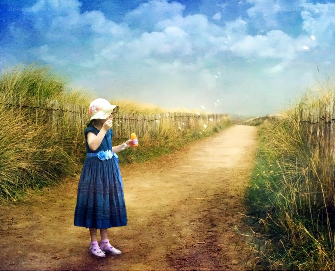 Girl blowing bubbles on a path