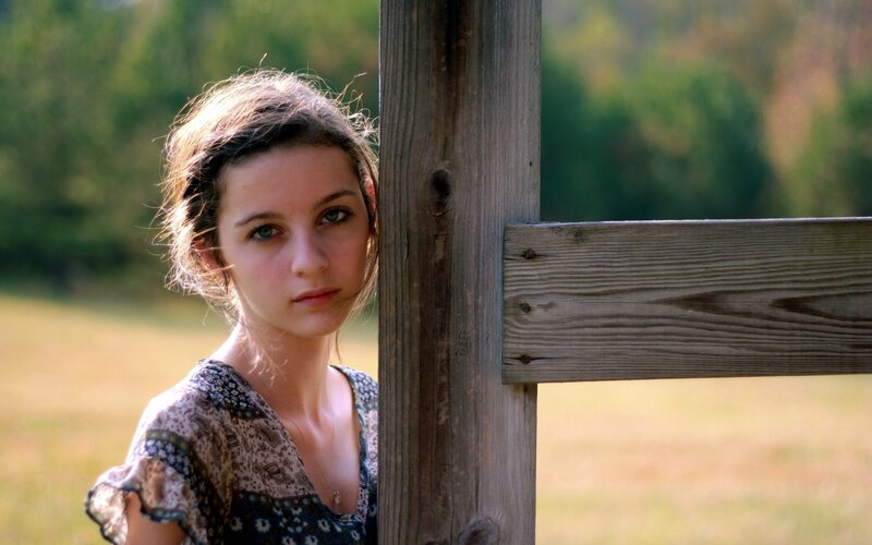 girl by wooden fence