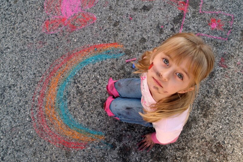 girl drawing rainbow with chalk