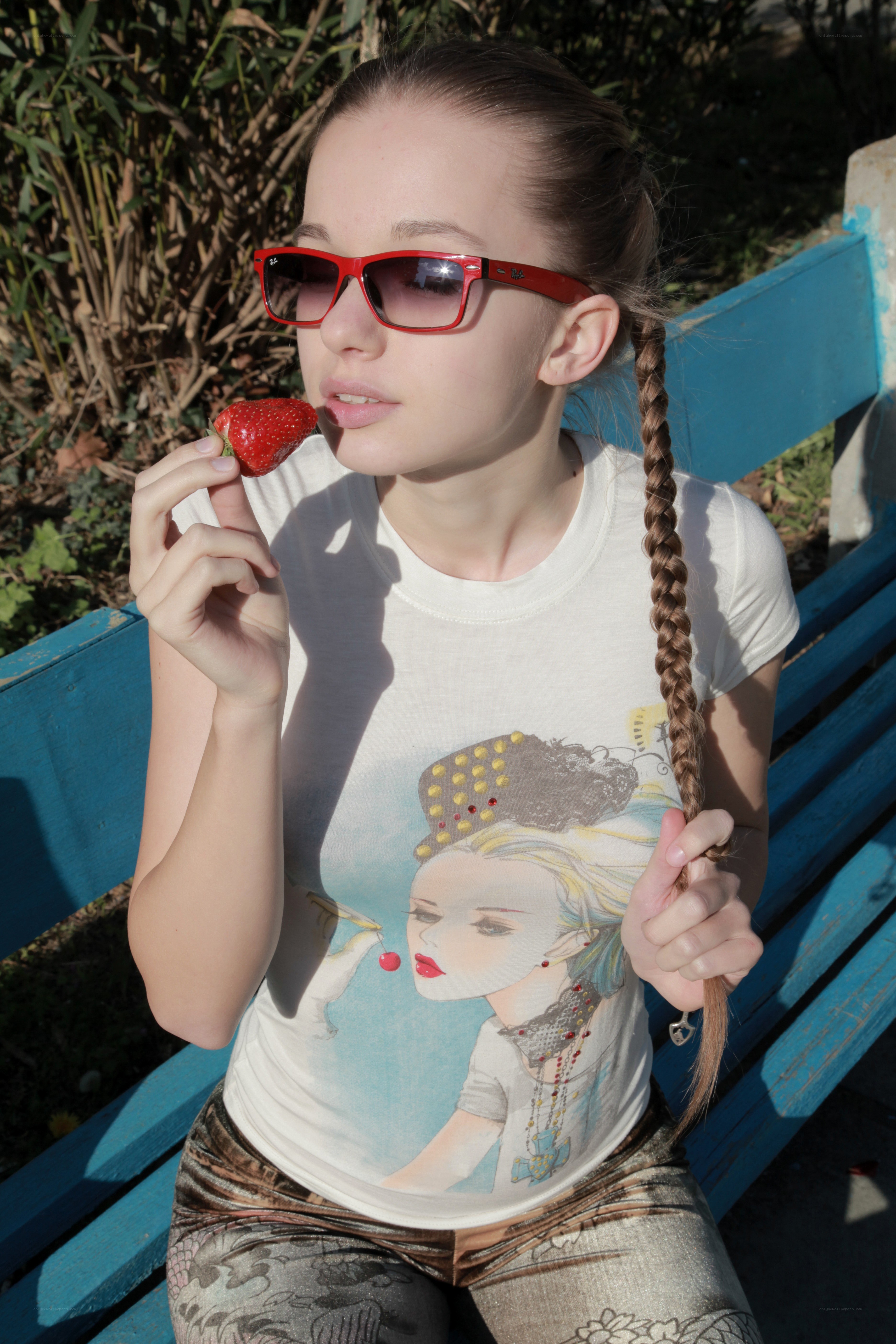 Girl eating strawberry on bench