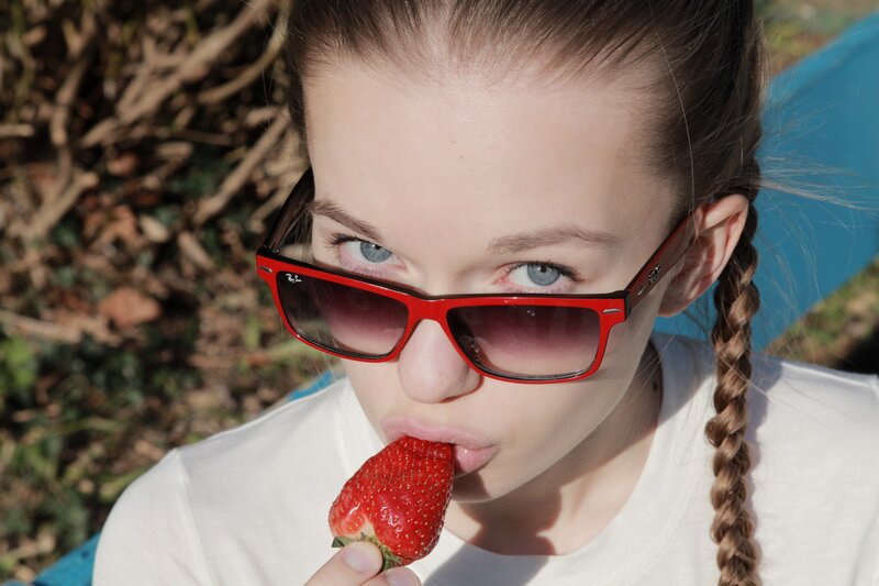 girl eating strawberry outdoors