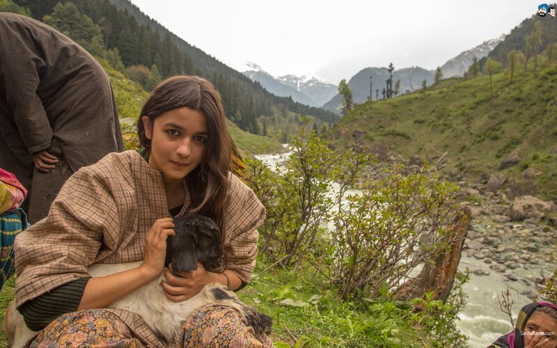 Girl holding a lamb in mountains