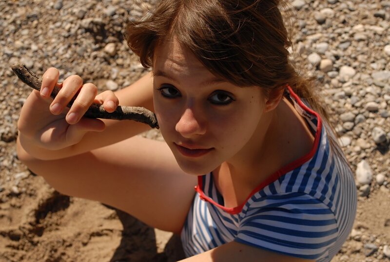 Girl holding a stick on pebbles