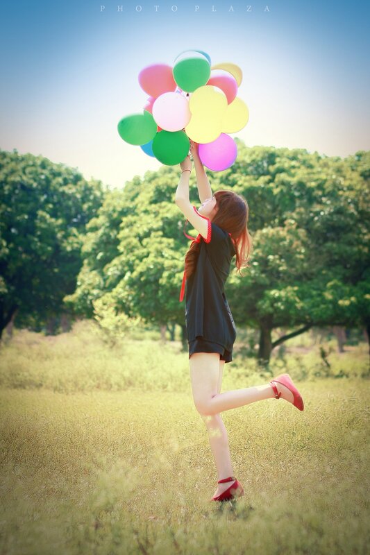 Girl holding balloons in a field
