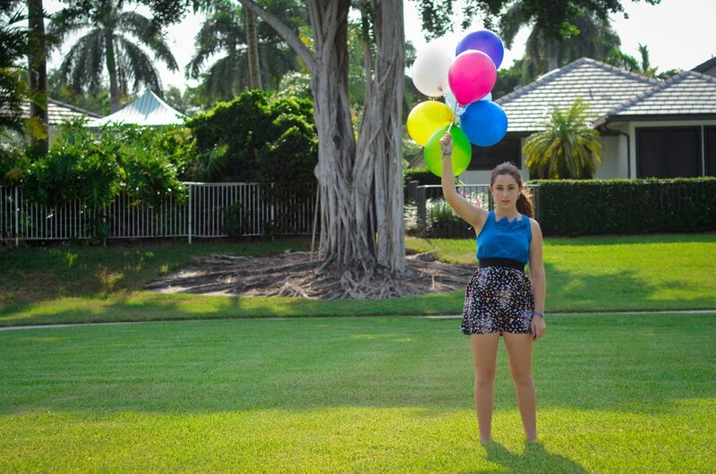 Girl holding balloons in a yard