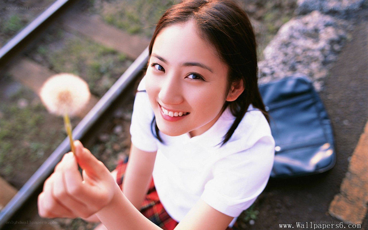 girl holding dandelion on train tracks