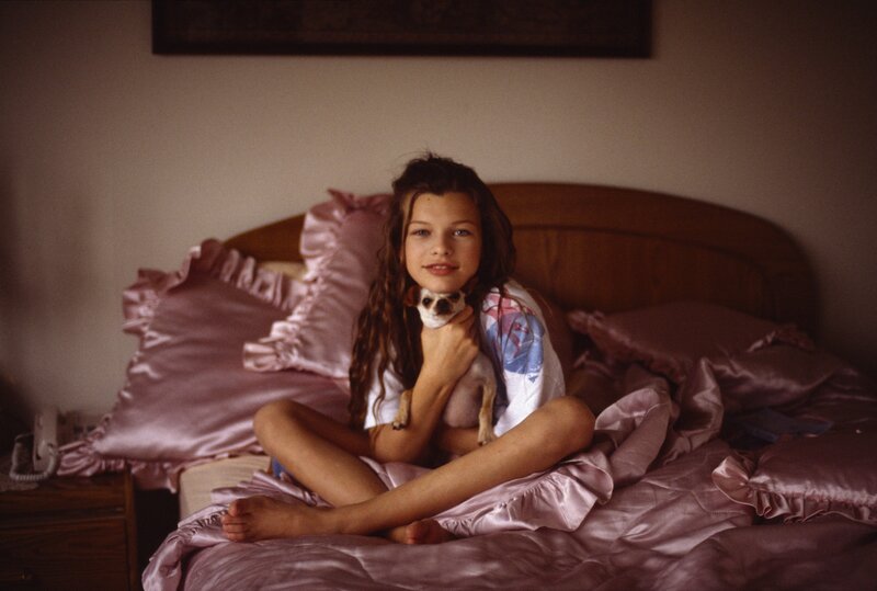 Girl holding dog on bed
