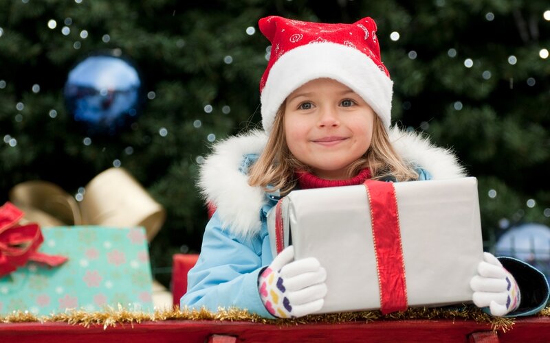 girl holding gift near christmas tree