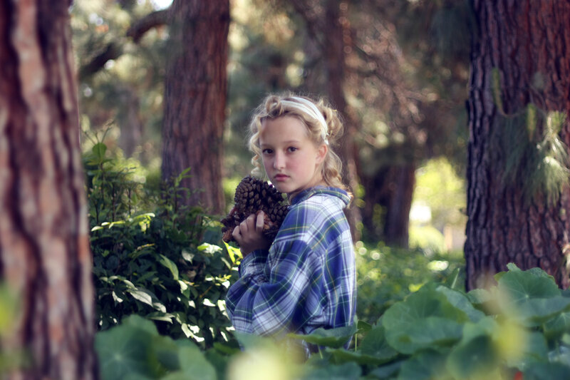 Girl holding pinecone in forest