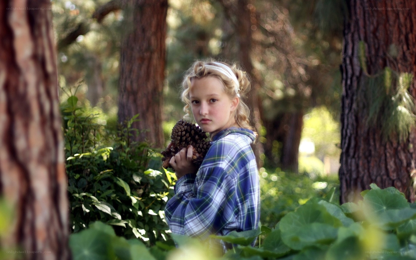 Girl holding pinecone in forest