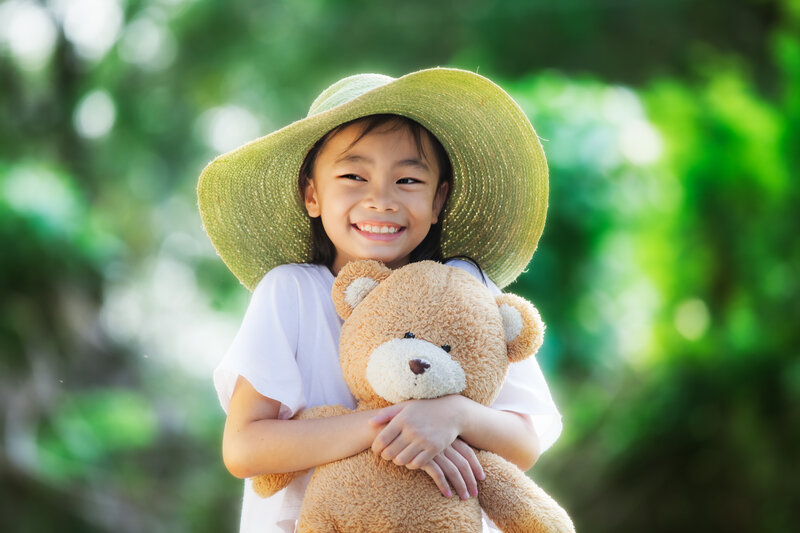 Girl Holding Teddy Bear — Green, Happy