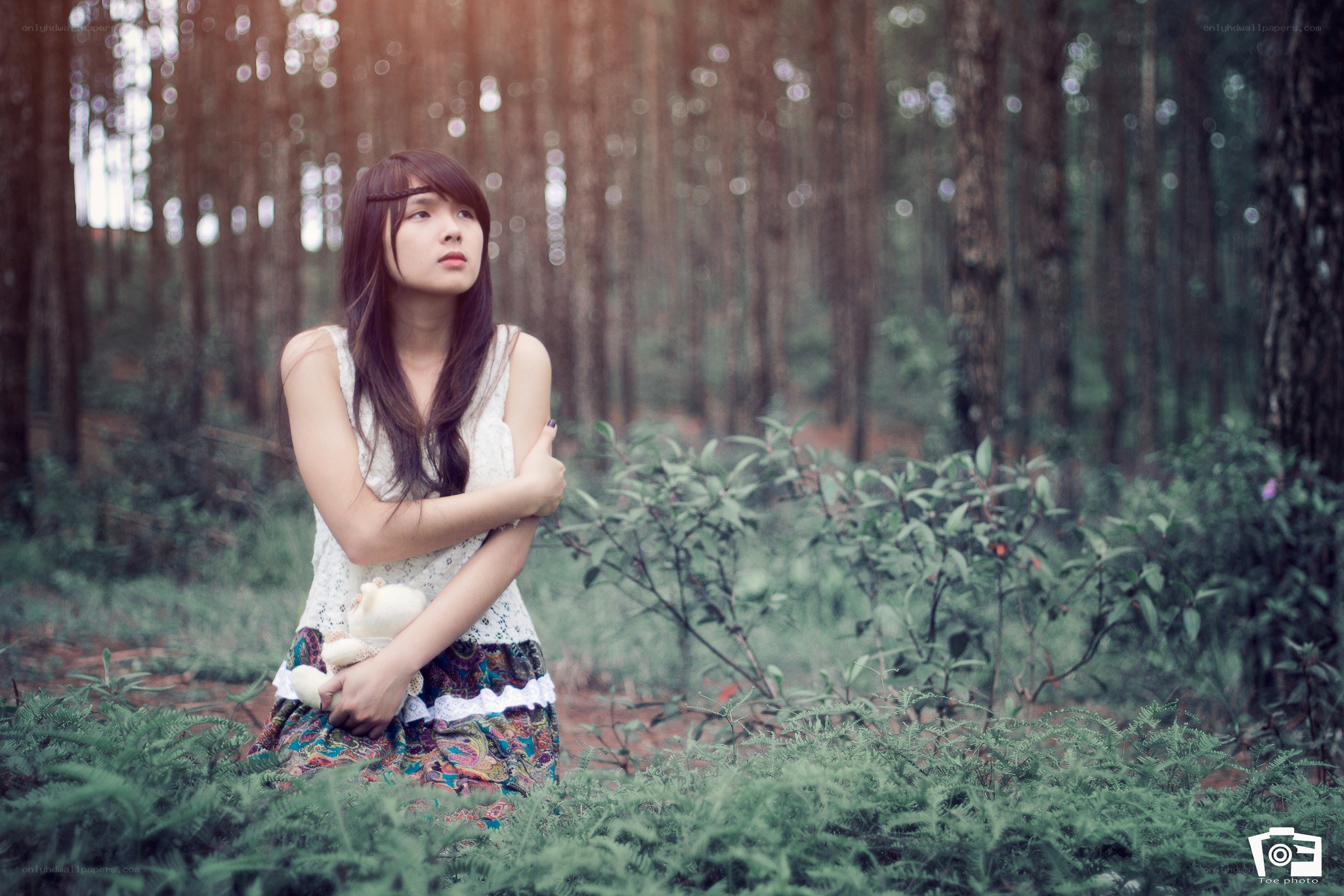 Girl holding teddy bear in forest
