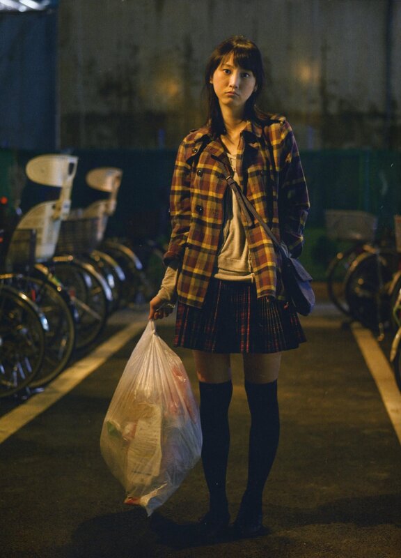 girl holding trash bag at night