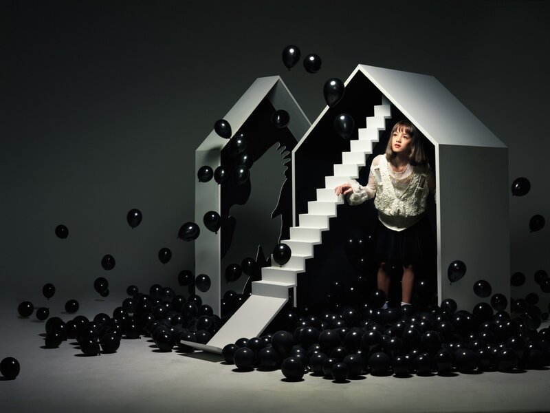 Girl in a house with black balloons