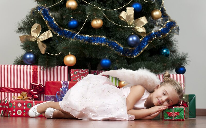 Girl in angel costume by Christmas tree