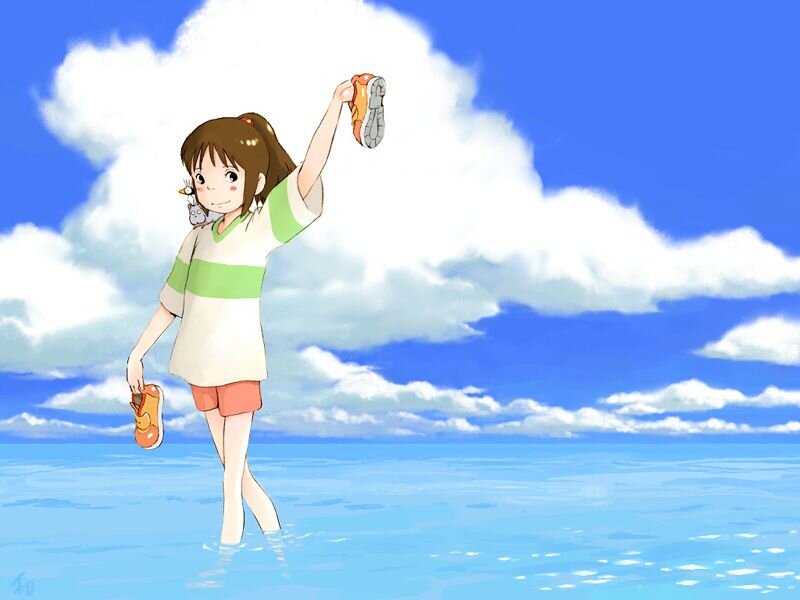 girl in ocean holding shoes