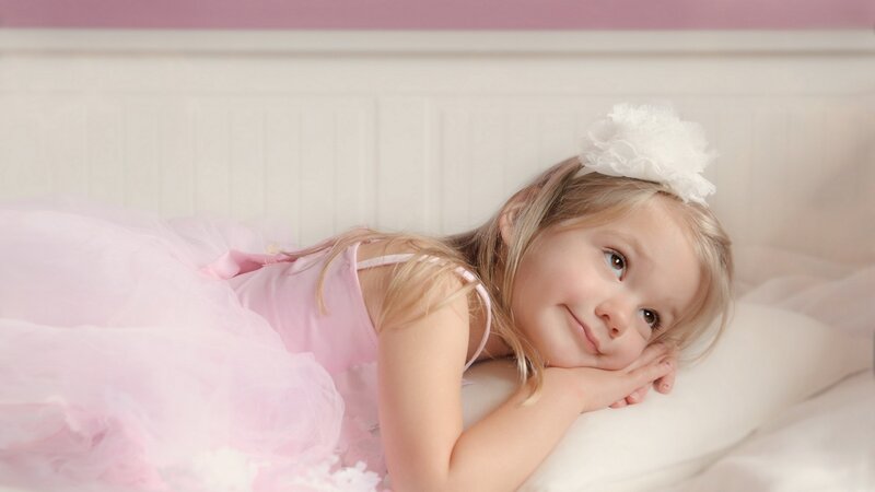 girl in pink dress lying on bed
