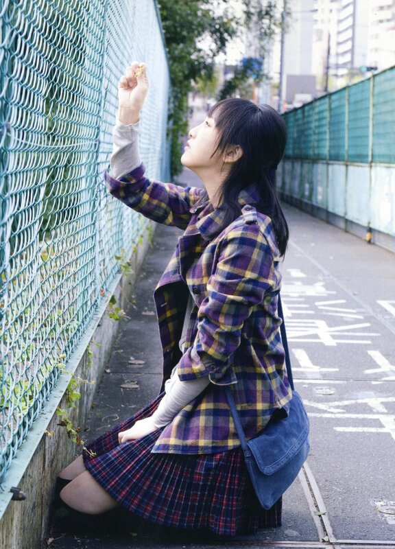 girl in plaid coat by fence