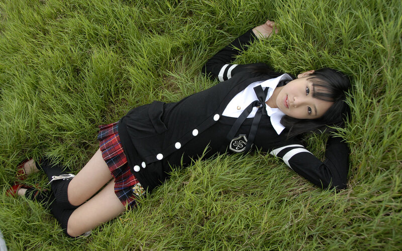 Girl in school uniform lying on grass