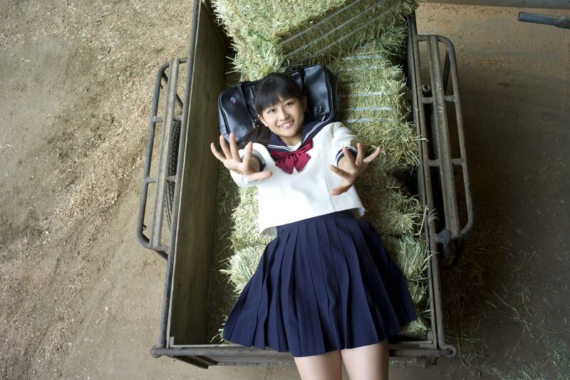Girl in school uniform on hay