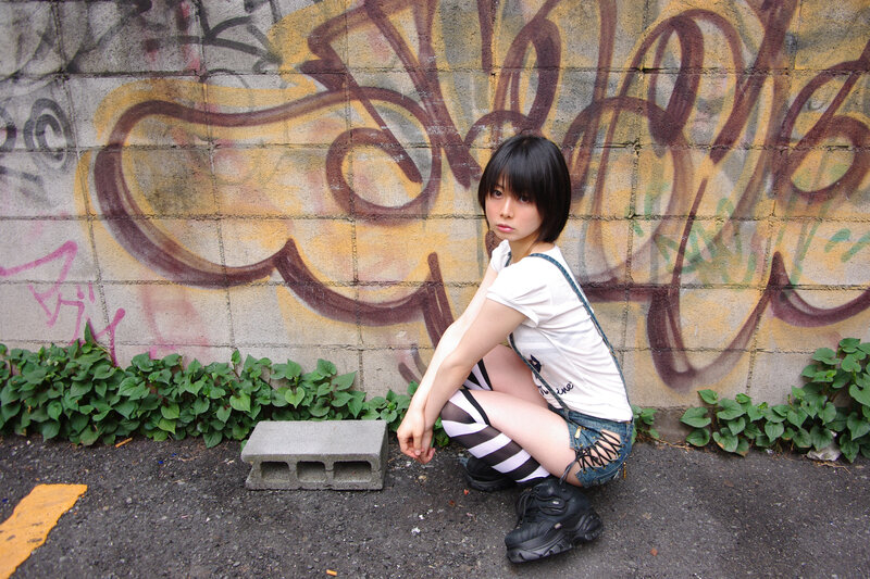 Girl in striped socks crouching by graffiti