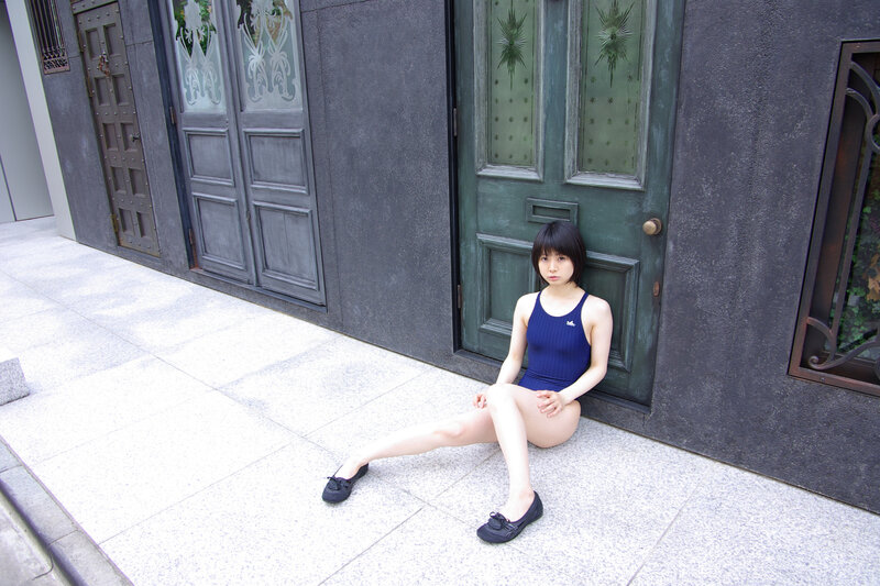 Girl in swimsuit sitting on sidewalk