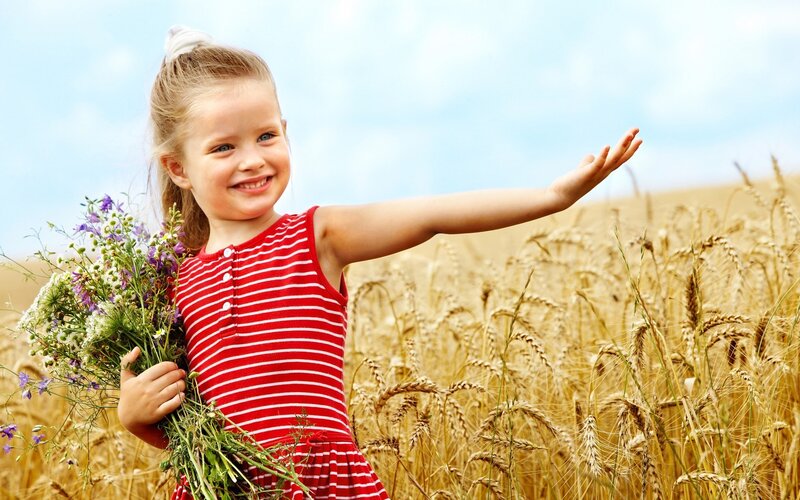 Girl in wheat field with flowers