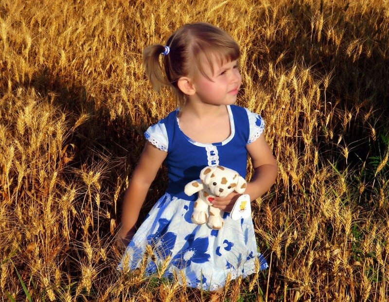 Girl in wheat field with teddy bear