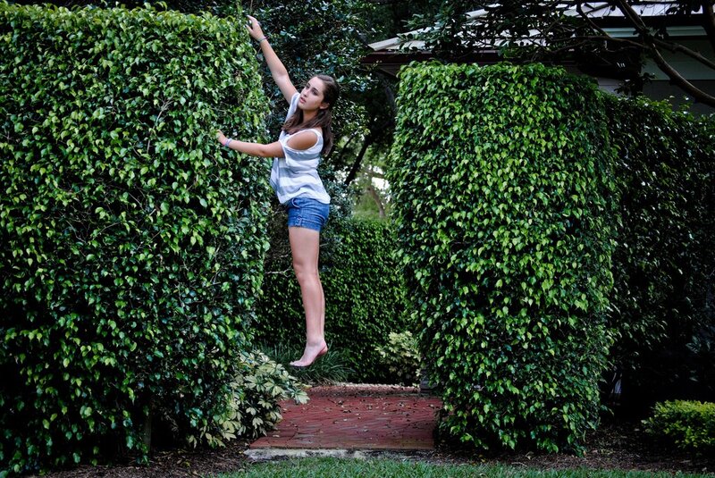 Girl jumping between hedges