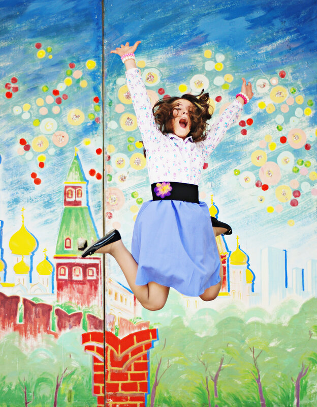 Girl jumping in front of painted backdrop