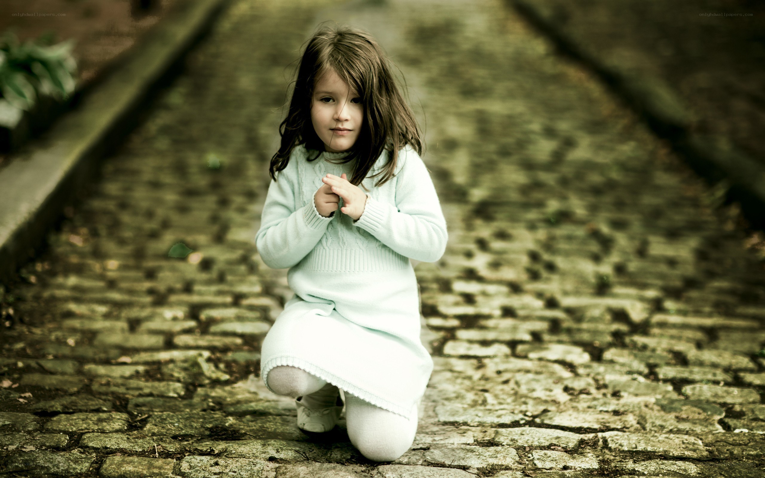 girl kneeling on cobblestone path