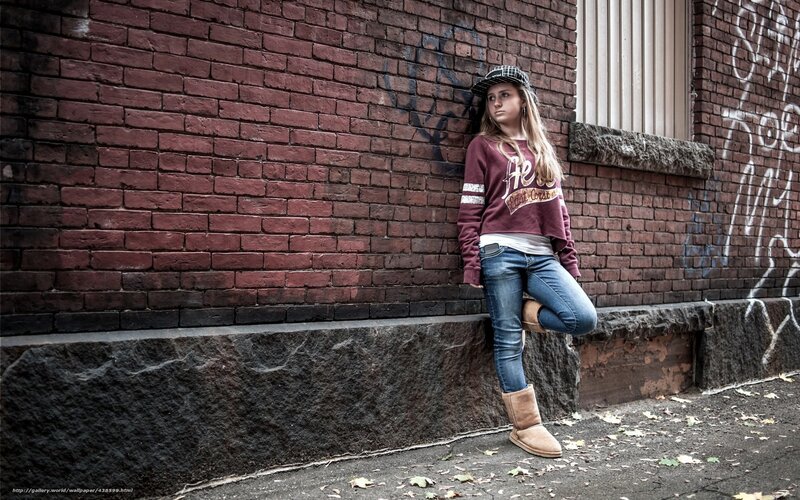Girl leaning against brick wall