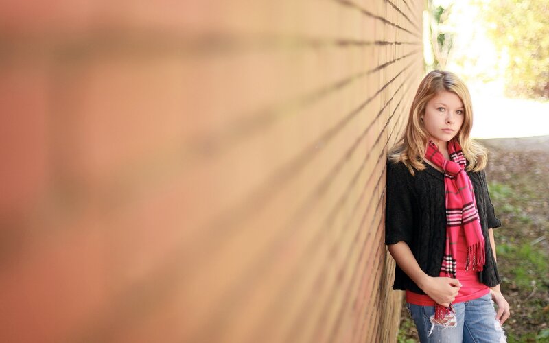 girl leaning against brick wall